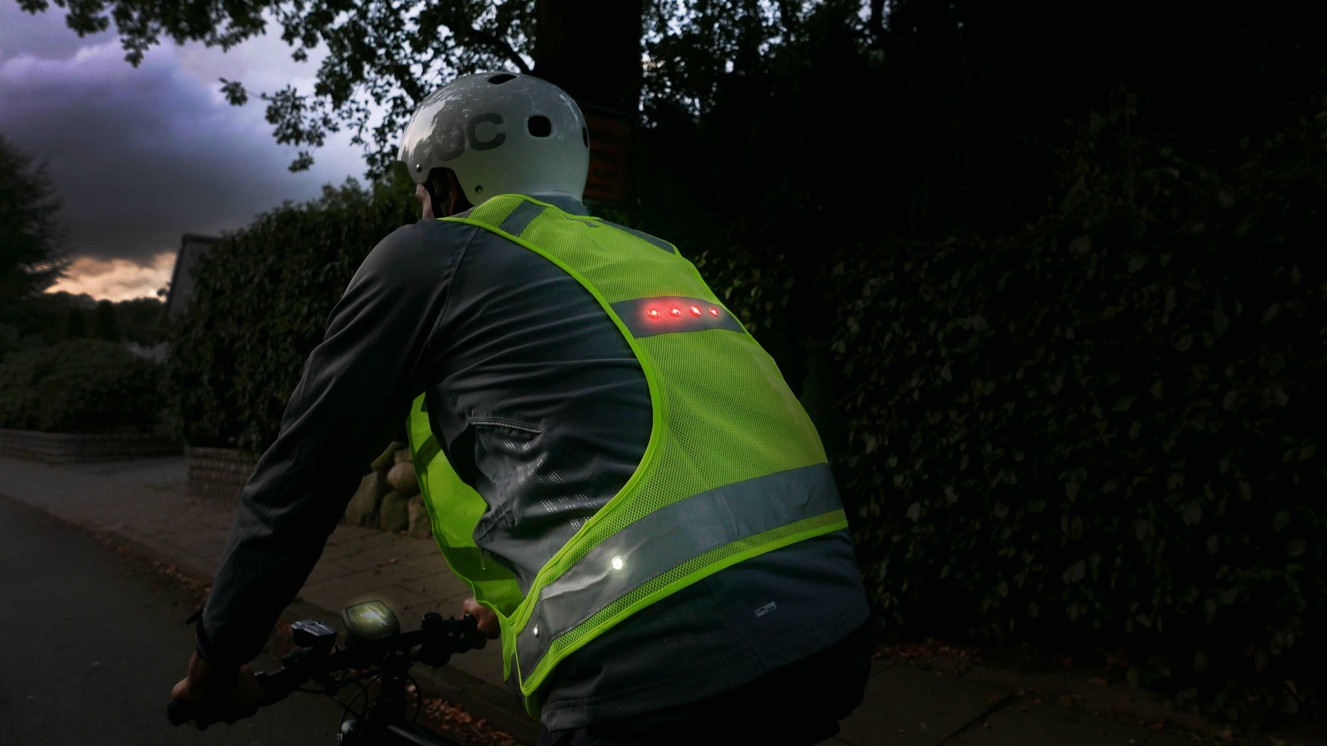 LED Sportweste mit leuchtenden LEDs an Fahrradfahrer im Dunkeln von hinten