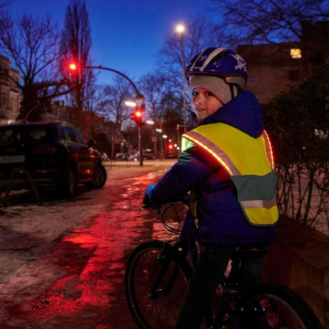 LED Warncape an Kind auf Fahrrad im Dunkeln – leuchtende LEDs im Straßenverkehr