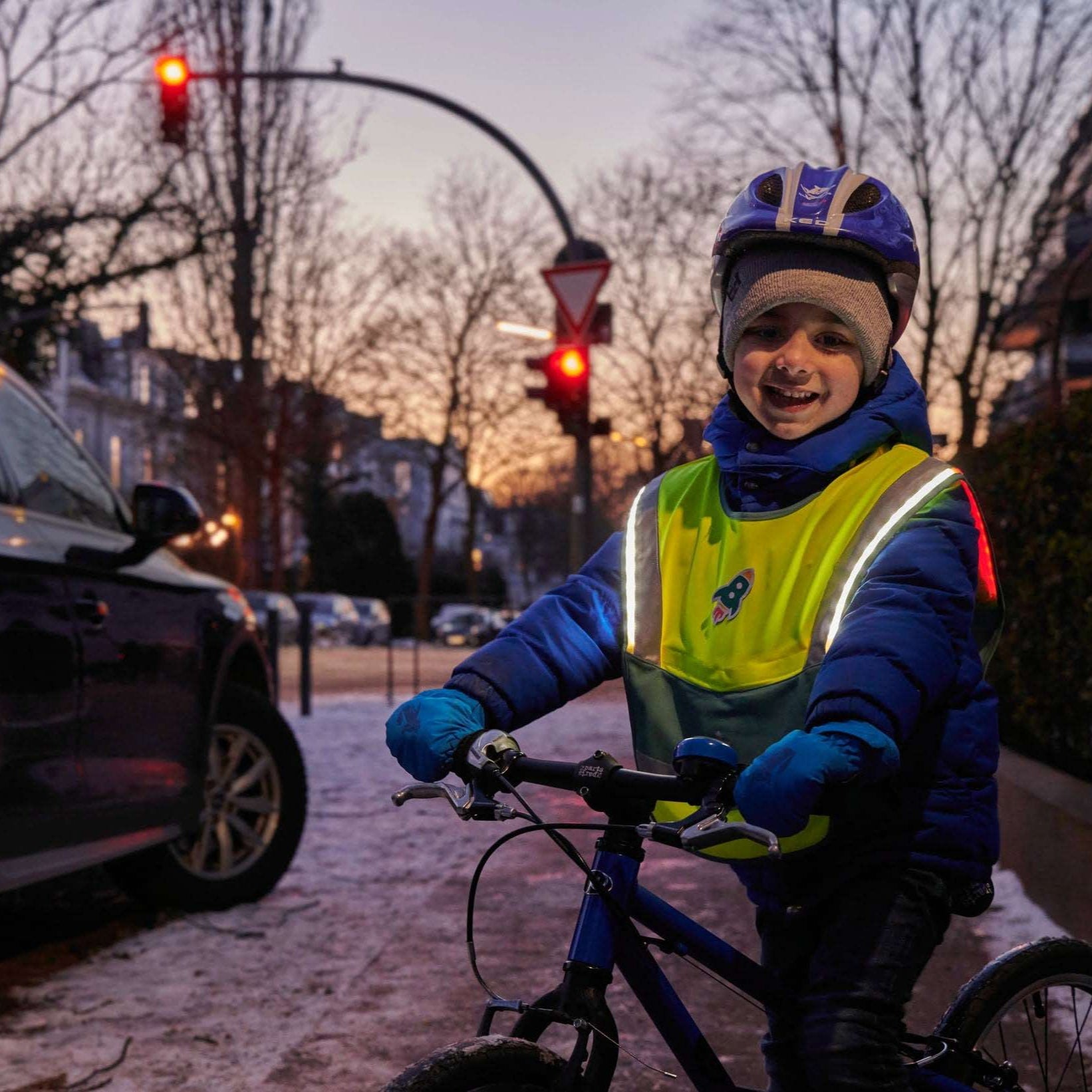 LED Warncape an Kind auf Fahrrad im Straßenverkehr – leuchtende LEDs