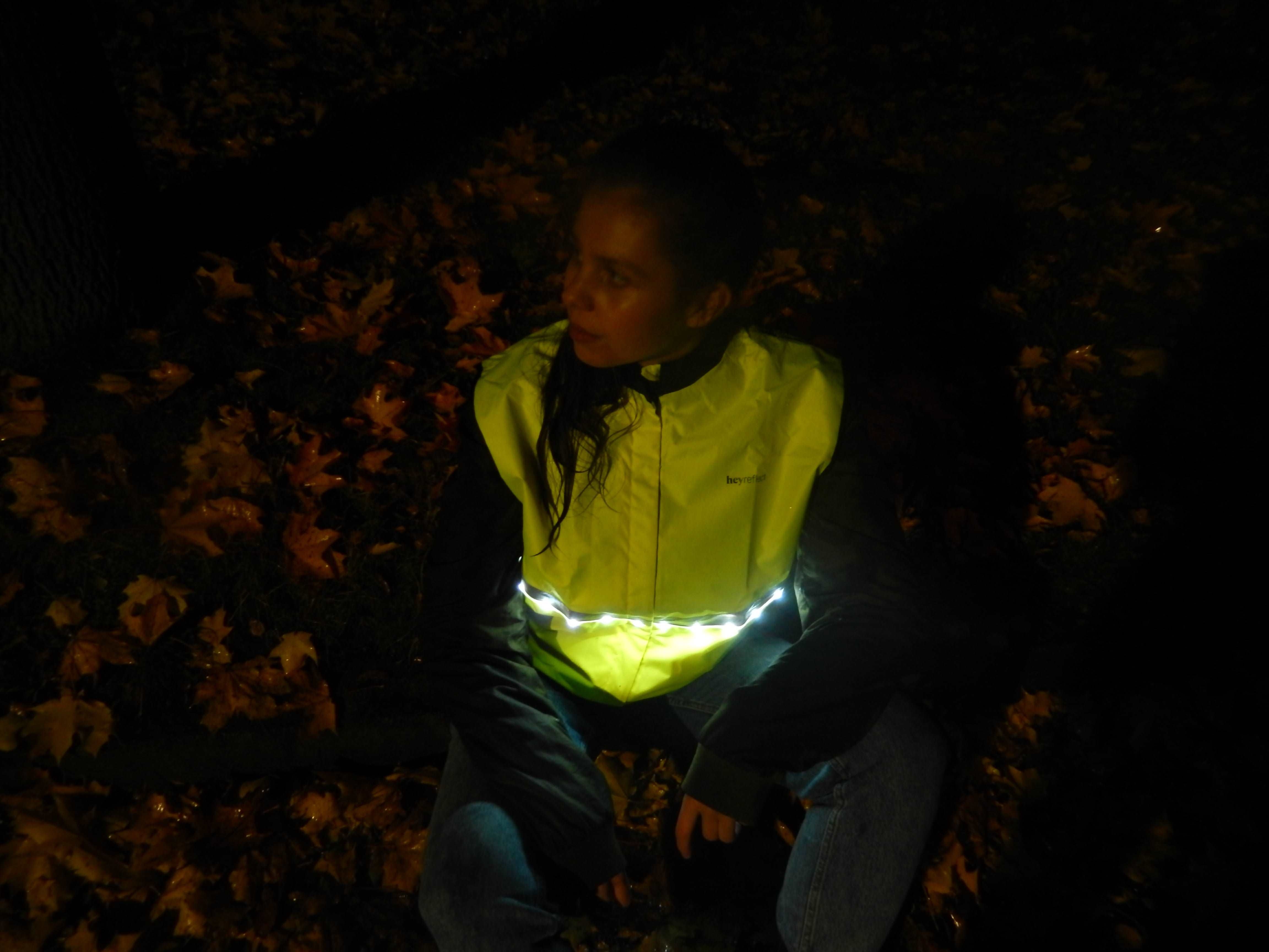 LED Warnweste für Erwachsene, Frau mit gelber Warnweste im Dunkeln – leuchtende LEDs