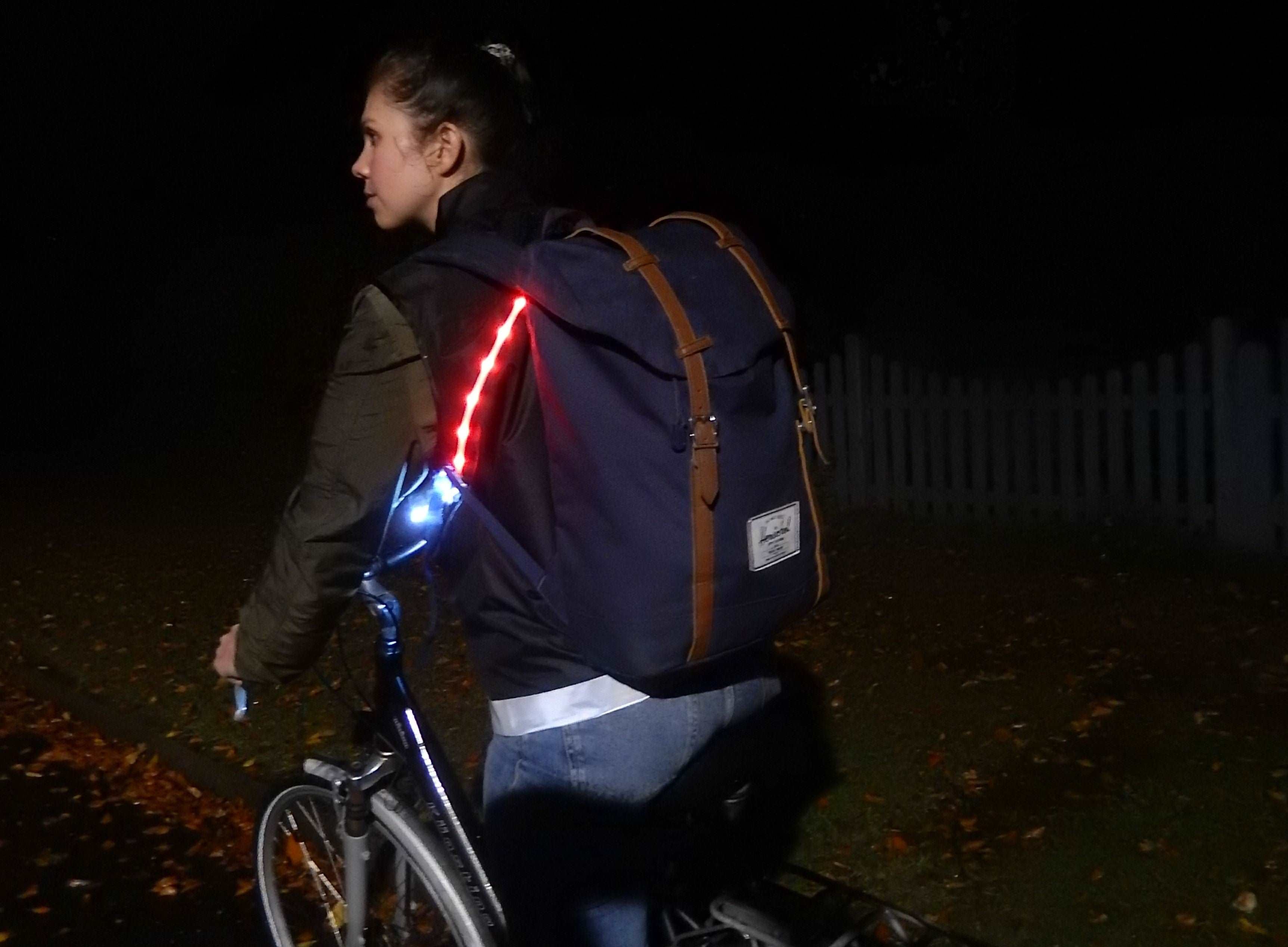 LED Warnweste für Erwachsene – Frau auf Fahrrad im Dunkeln mit leuchtenden LEDs
